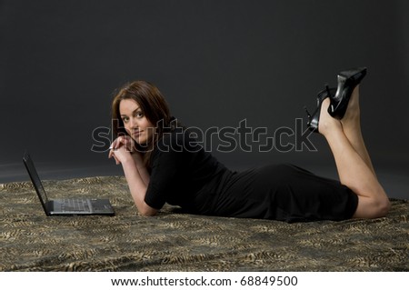 Portrait of sexy woman in black dress with laptop over black