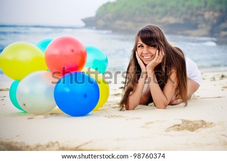 beautiful  girl lying with  bunch of colorful air balloons at the beach
