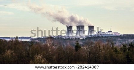 Impressive cooling towers of nuclear power plant Temelin, behind nice winter forest in lovely landscape