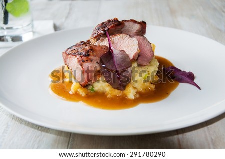 Pork tenderloin with pear sauce on white plate on white table