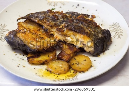 Grilled catfish with sliced potatoes on white plate
