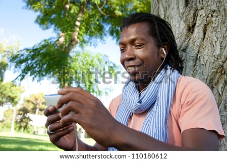 Black Jamaican man on a video call using his mobile phone in a park.