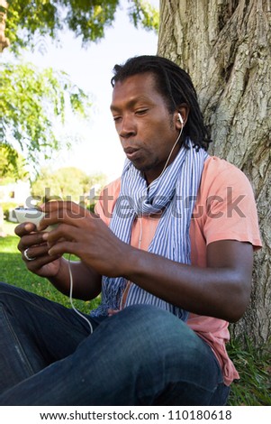 Black Jamaican man on a video call using his mobile phone in a park.