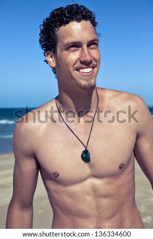 Young handsome muscular man in a bathing suit hanging on the beach. Surfer type. Retro look.