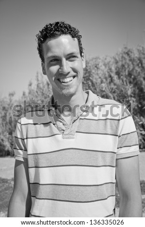 Handsome young man smiling in front of a corn field. Black and white.