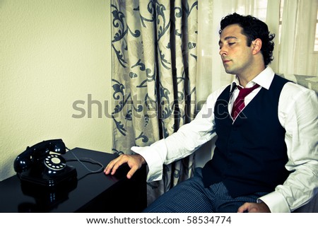Retro - dressed up handsome man looking at an old telephone
