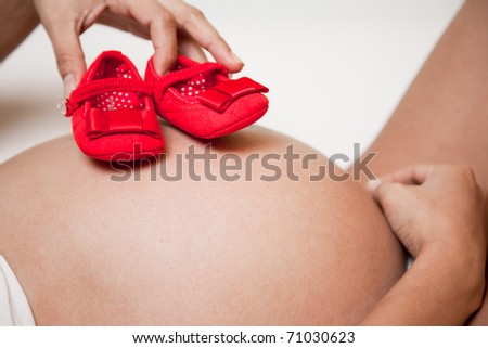 Pregnancy belly with red shoes on top in a clear background