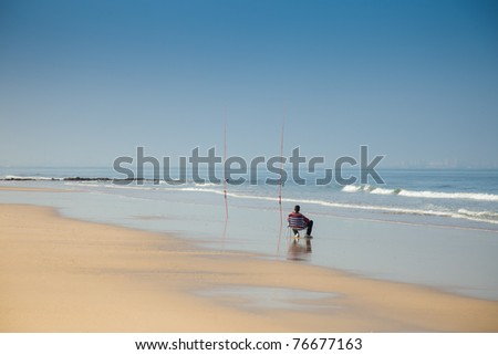 Fisherman sitting next to his fishing rods waiting for fish.
