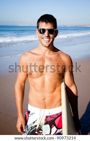 Handsome muscular surfer wearing sunglasses smiling at camera.