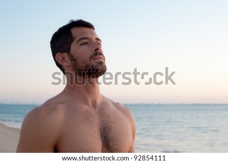 Handsome muscular man deep breathing on the beach.