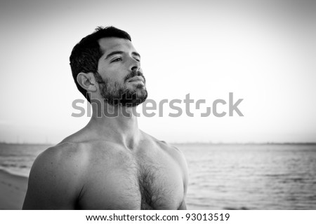 Handsome muscular man deep breathing on the beach. Black and white portrait.