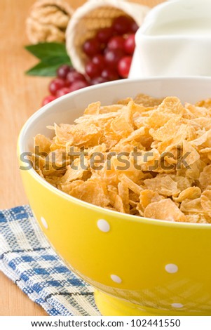 Bowl of corn flakes with berry and milk on wood