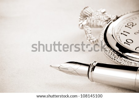 ink pen and watch on parchment background texture