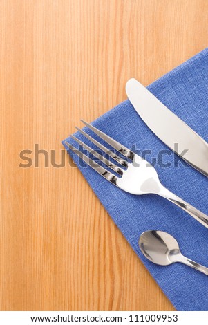 silver fork and knife as utensils on napkin at wooden background