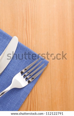 silver fork and knife as utensils at napkin on wooden background