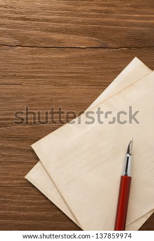 ink pen and old postal envelope on wood background