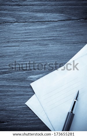 pen and old postal envelope on wood background