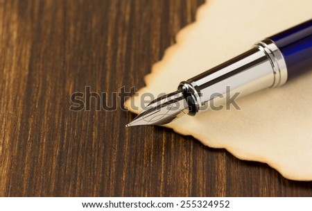 ink pen and paper parchment on wooden background