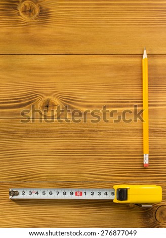 tape measure and pencil on wooden texture