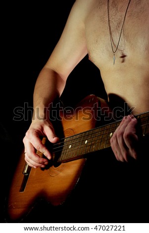 man without shirt holding guitar at black background