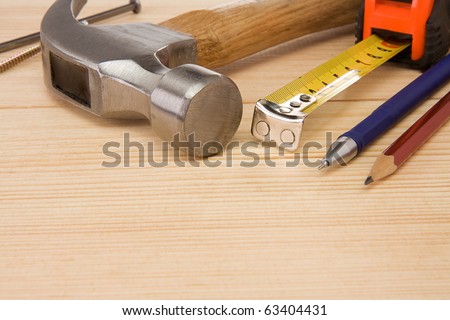 hammer, tape measure, nail and pencil on wood brick