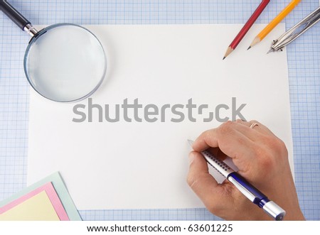 male hand writing by pen and magnifying glass on graph grid paper