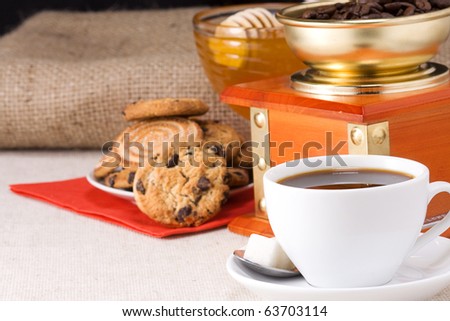 cup of coffee, honey and grinder witn cookies on sacking