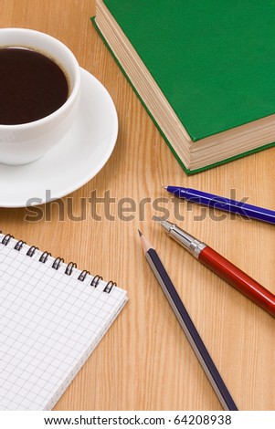 cup of coffee, book, pencil and pen with notebook on table