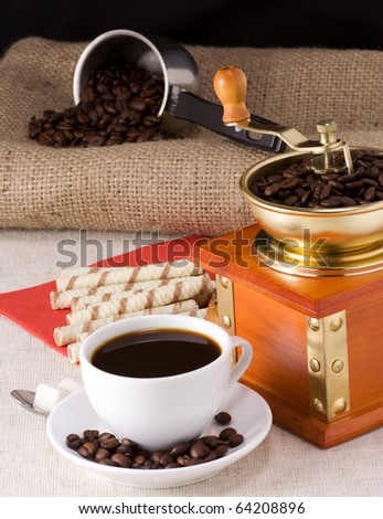 coffee beans, honey, cup and grinder on sacking