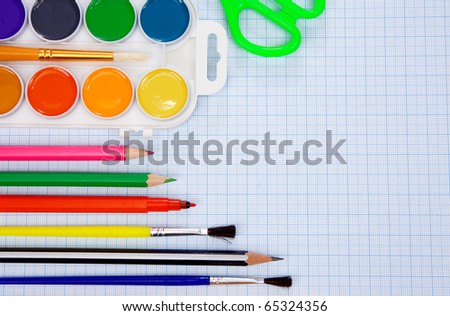 pencils, felt pens, paint brush and scissors on graph grid paper