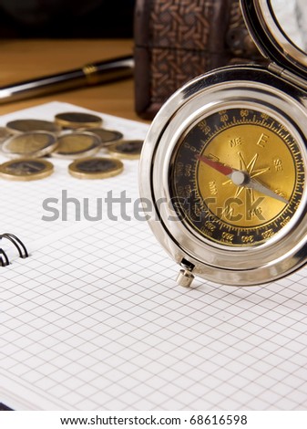 compass, gold coin and pen on checked notebook