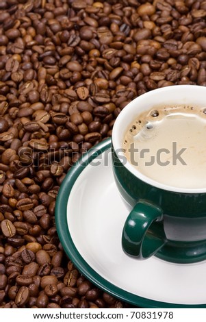 green cup of coffee on beans