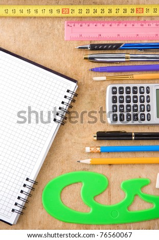 school, office accessories and checked notebook on wooden texture