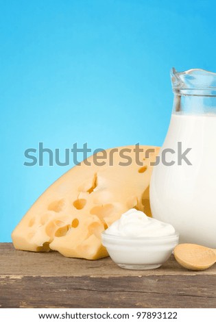 swiss cheese and milk products on wood at blue background