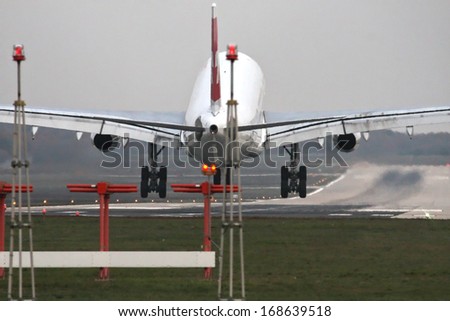 Airplane with four engines landing on runway back view - moments before touchdown