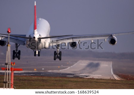Airplane with four engines landing on runway back view - moments before touchdown