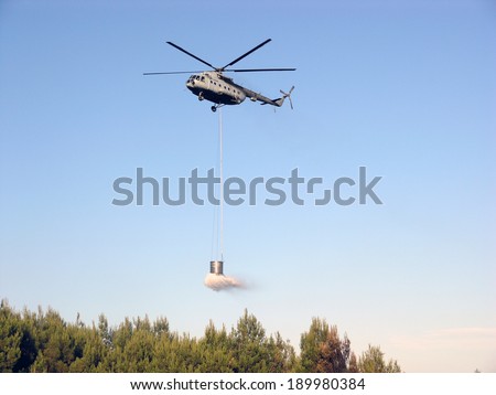 Fire fighting helicopter over burning forest
