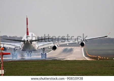 Airplane with four engines landing on runway back view - touchdown with tire smoke