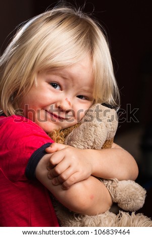 A cute injured little boy hugs his stuffed toy