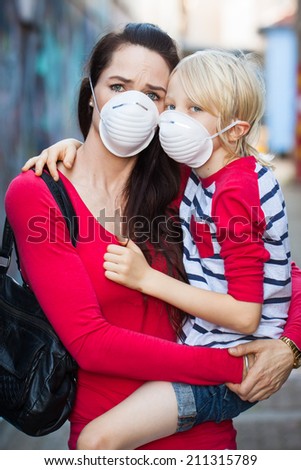 A concerned woman and her son wearing protective face masks for pollution or virus.