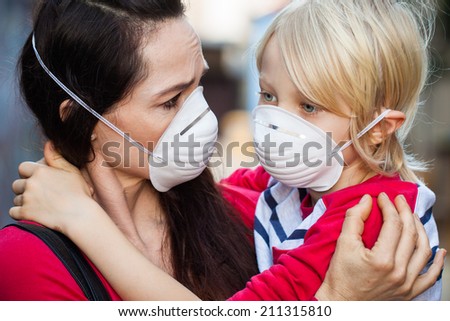 Close-up of a  concerned woman looking at her sick son. Both are wearing protective face masks for pollution or virus.