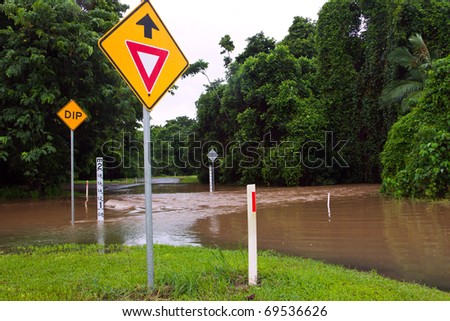 Flooded road with depth indicators and give way and dip road signs  after heavy rain and flooding in Queensland, Australia