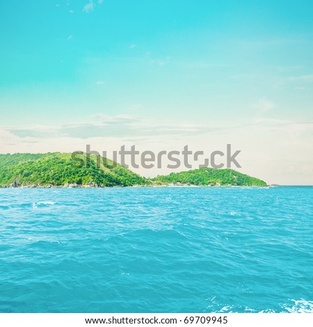 Tropical island in ocean. Blue sky and water