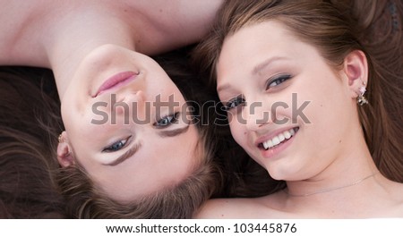 Two young happy women lying head to head portrait