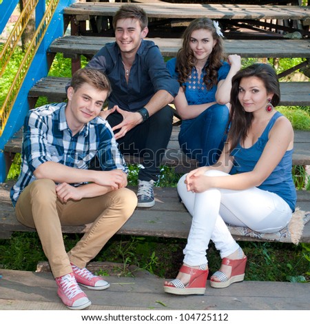 Group of four young people happy smiling having fun by posing outdoors in spring or summer on the bridge stairs