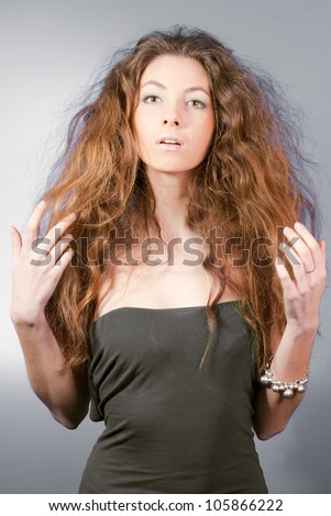 Portrait of a Beautiful woman excited presenting or showing with two arms touching her hair  in studio on the gray background