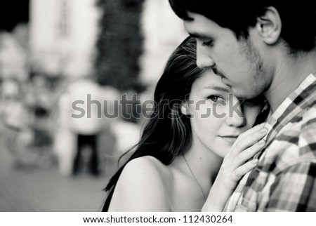 Young couple man and woman embracing tenderly in crowd outdoors black and white shot