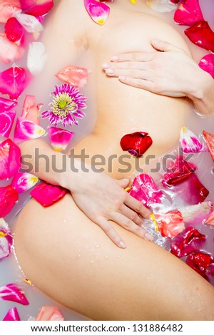 Beautiful sexy young woman in bath with flowers petal. Spa body care.