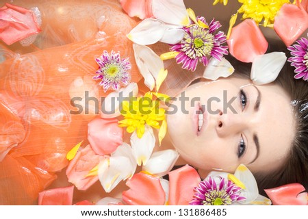 Beautiful sexy young woman in bath with flowers petal. Spa body care.