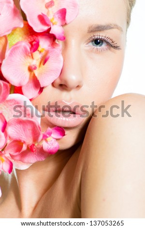 Closeup portrait of a beautiful young woman face with perfect skin & lips, pink flowers around face on white copyspace background